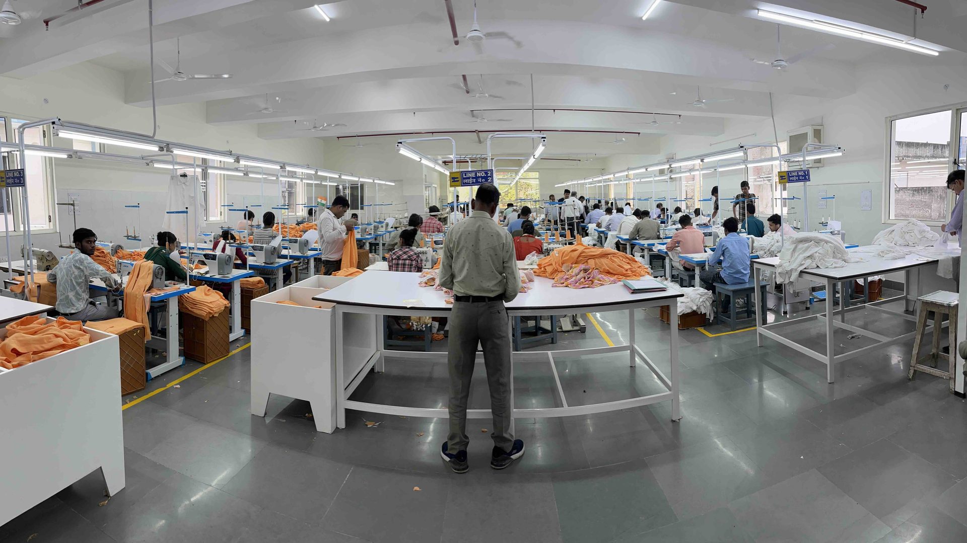 Wide-angle view of the Myra Enterprises garment manufacturing factory floor, Noida India